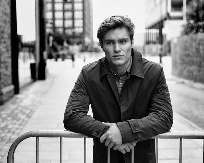 Dark outside black and white portrait photo of white male leaning on a railing.